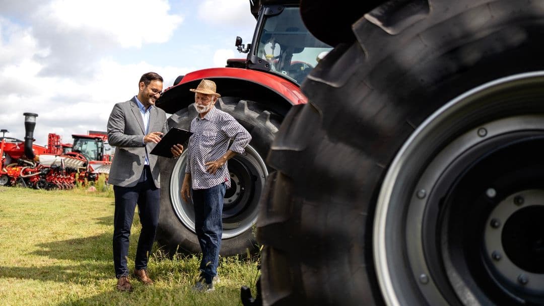 two men in field of tractors
